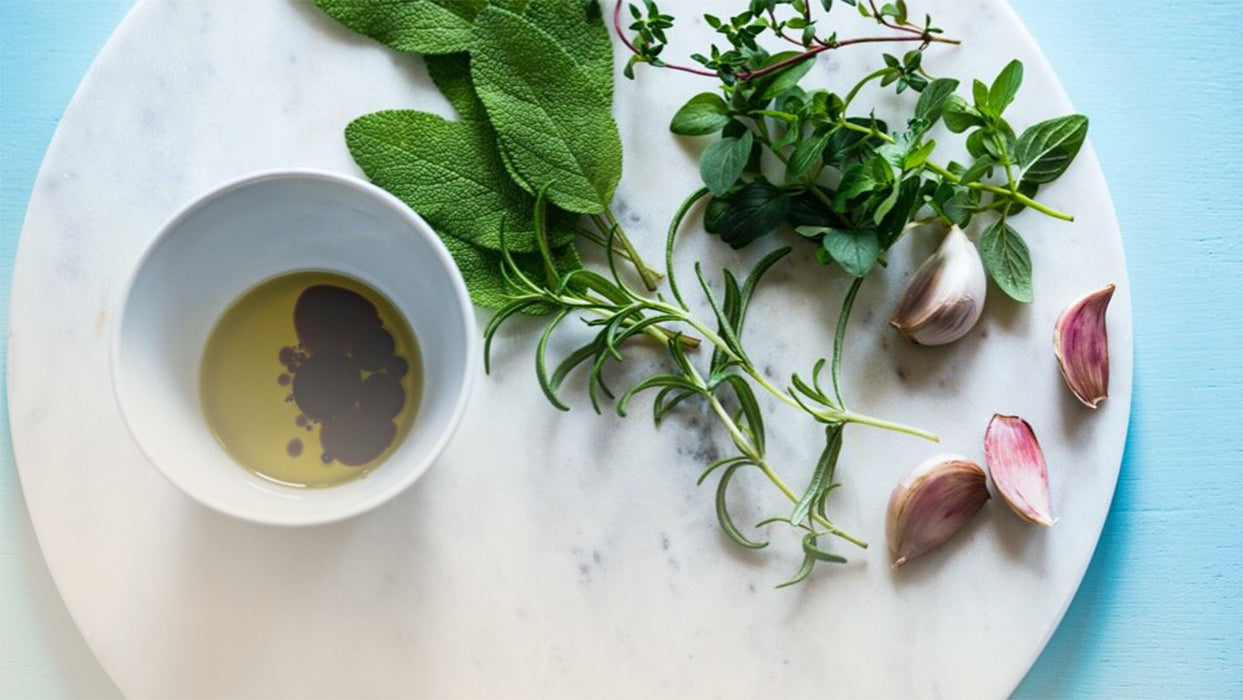 Mamorplatte weisses Gefaess mit Essig Knoblauchzehen Kraeuter